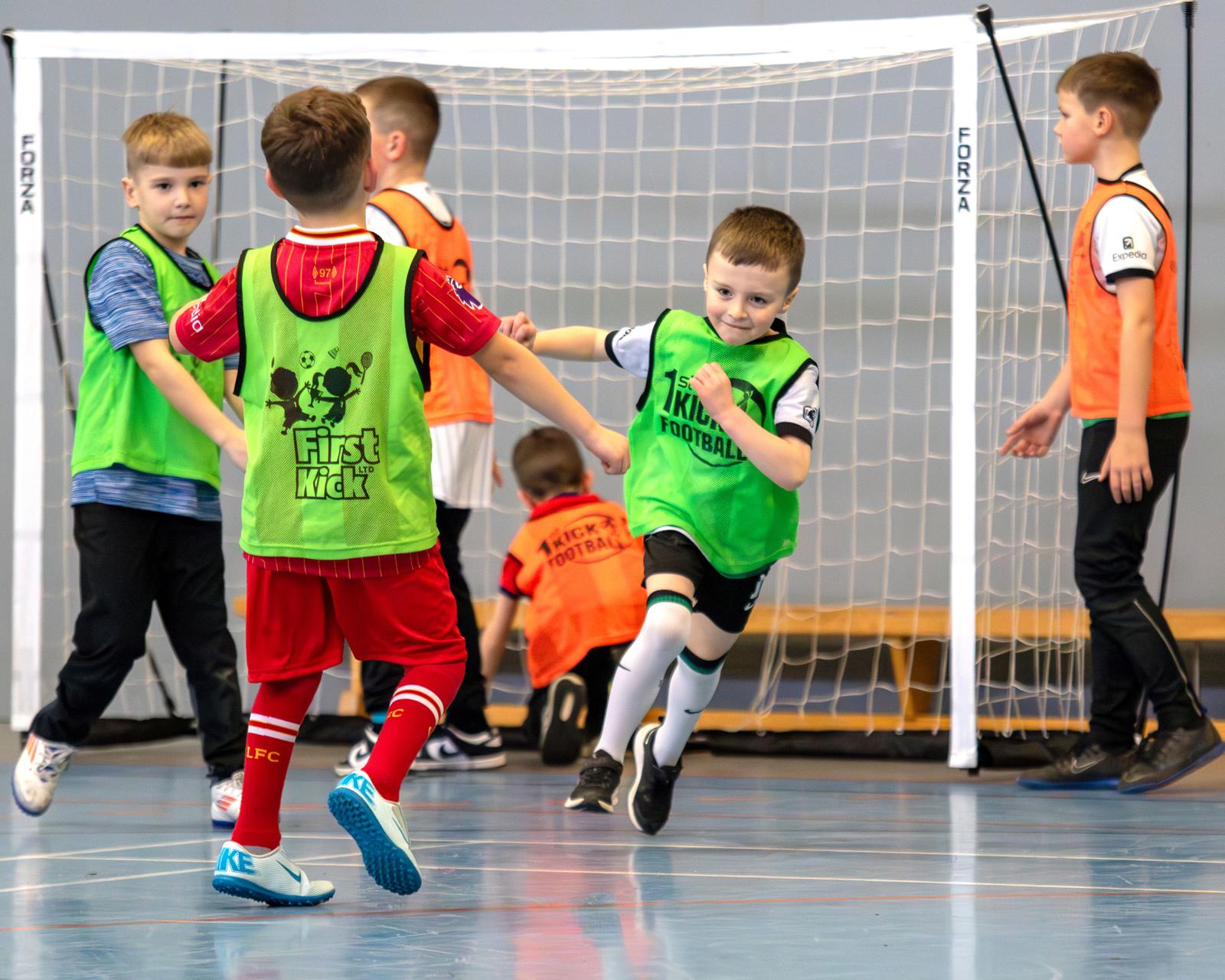 Children in First Kick bibs celebrating a goal