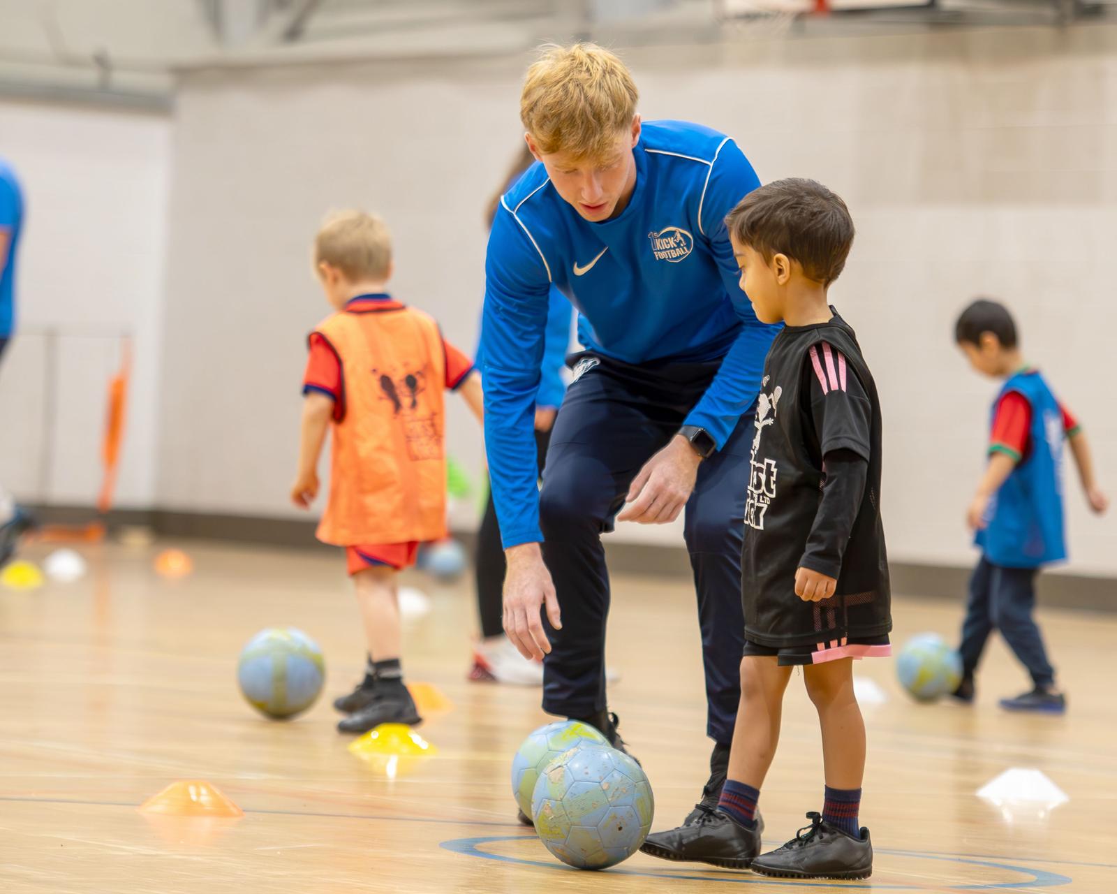 A First Kick coach showing a young player how to control the ball